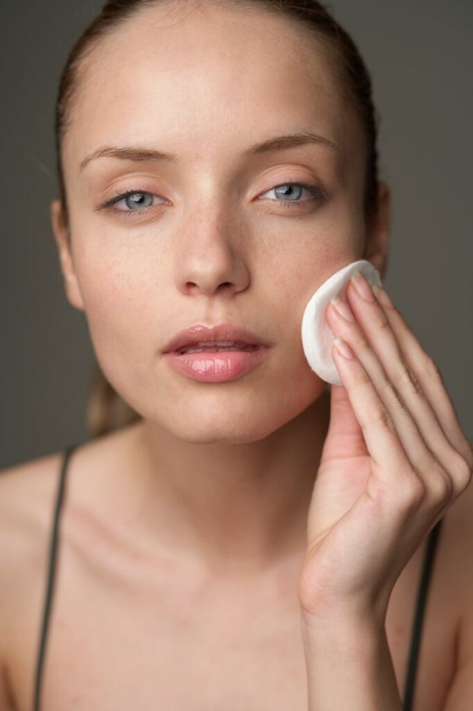 Young woman using a cotton pad for skincare, highlighting beauty routine.