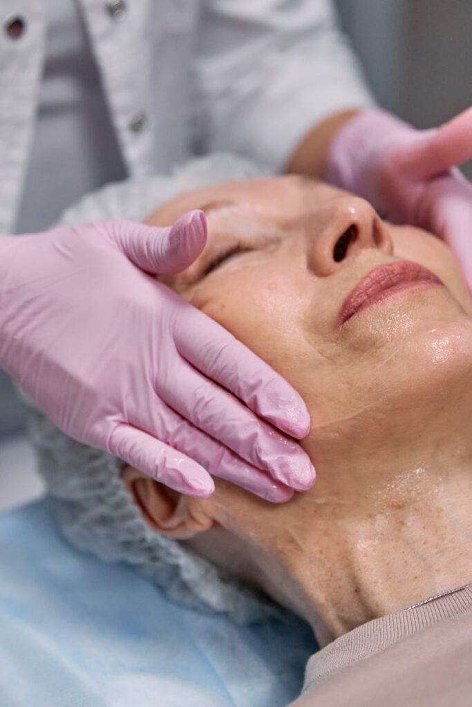 A senior woman enjoys a facial massage at a spa, promoting relaxation and skincare.